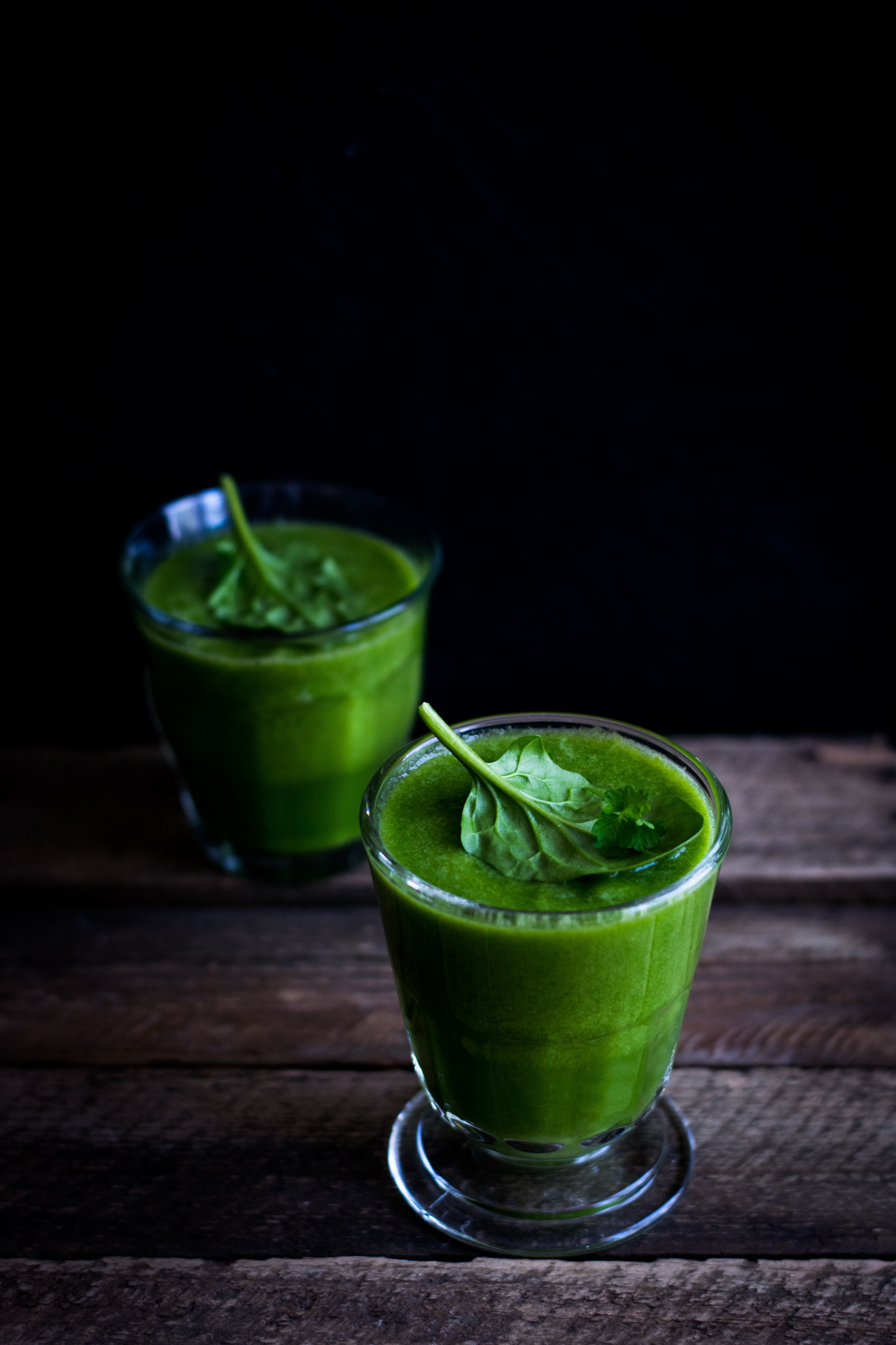Tow green smoothies in glass on wood table