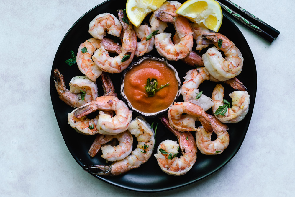 Roasted shrimp with peach habanero cocktail sauce on black plate